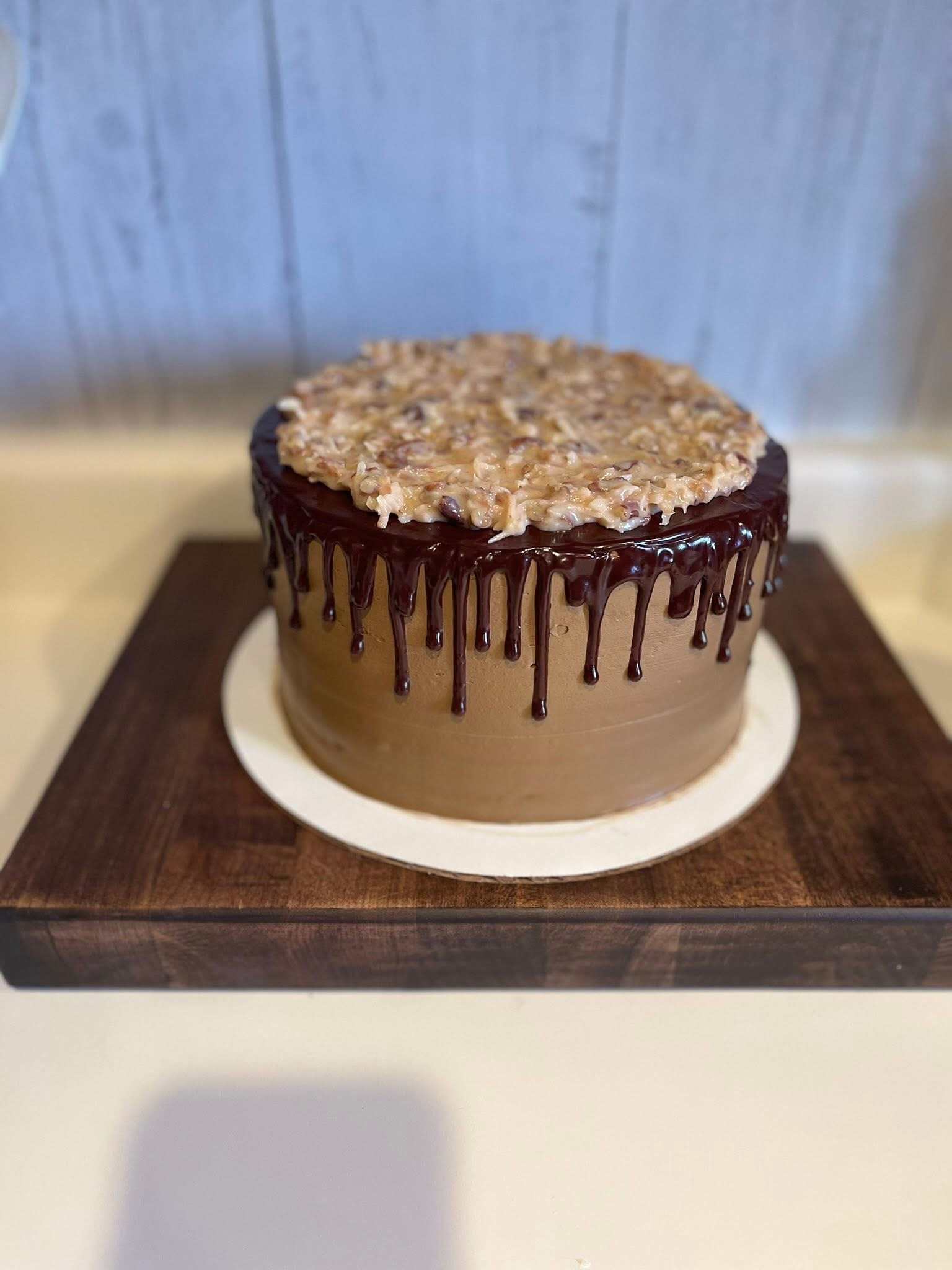 Round cake with chocolate drip icing on a wooden table